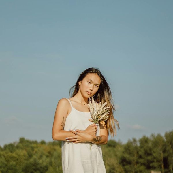 Person in a relaxed stretching pose, looking serene and content in a sunlit room.