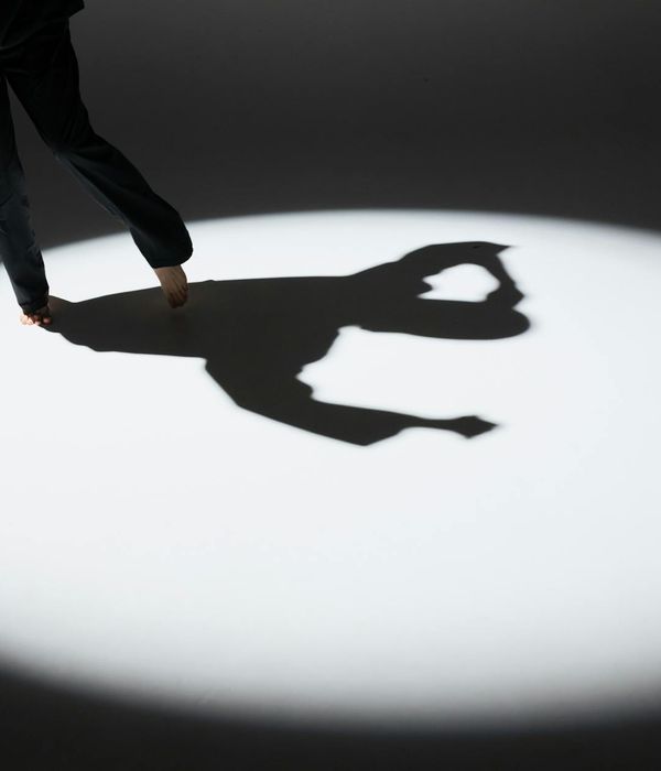 Woman performing a fluid, gentle cardio movement in a minimalist dark studio.